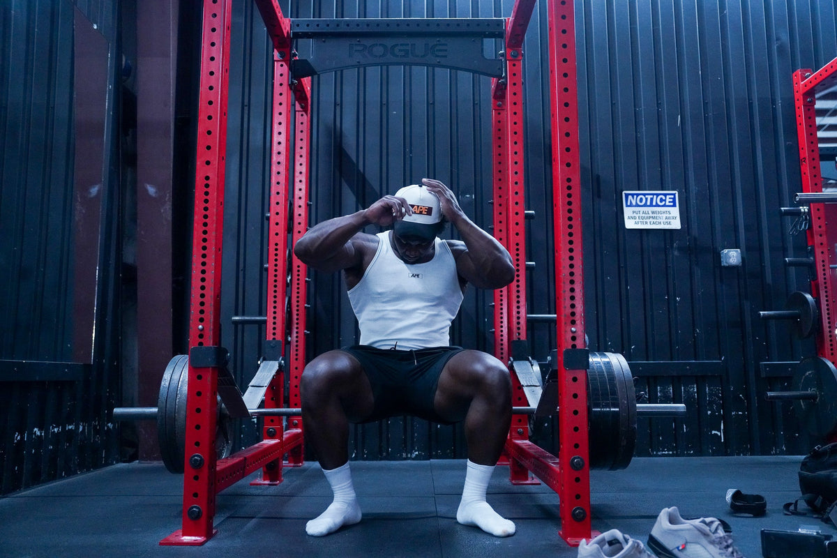 Athlete in The Tank sitting in a red squat rack
